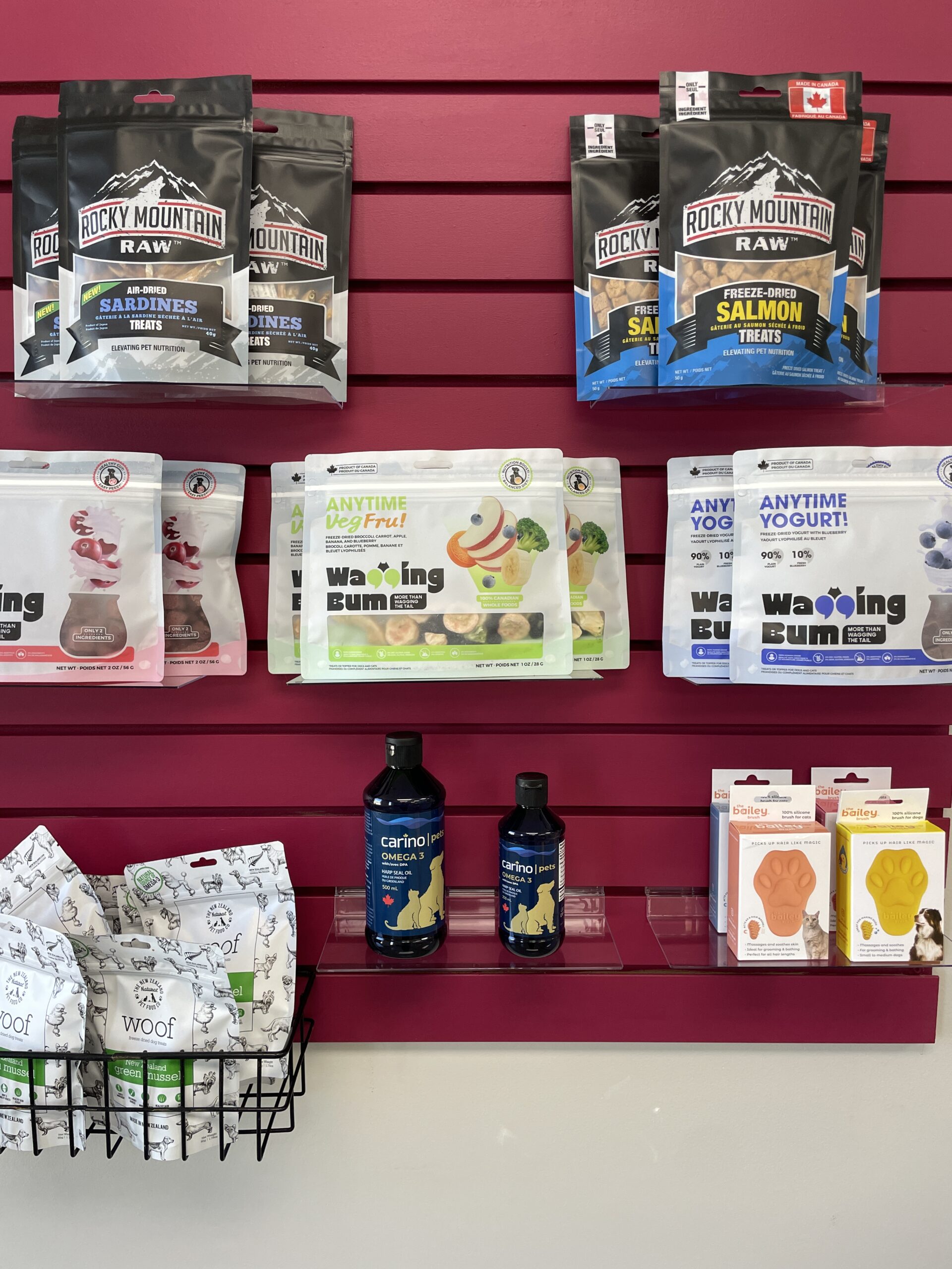 Pet Emporium treats and supplements are displayed on a red wall. Products include Rocky Mountain Raw, Anytime BitzFruit, Woof Wild, Carino, and Waggling Yums.